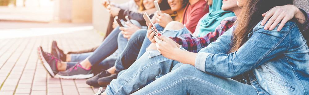 Jugendliche sitzen und starren aufs Smartphone